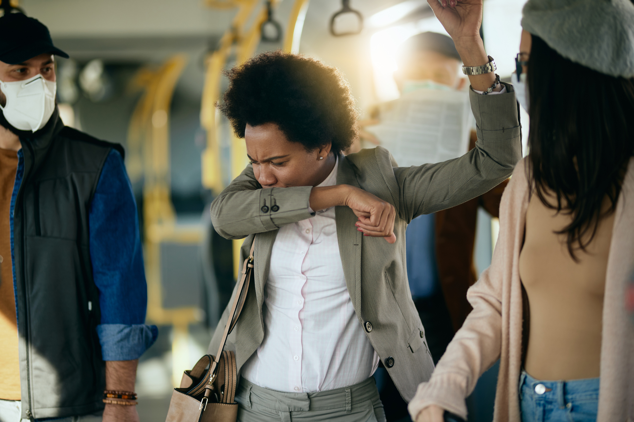 businesswoman coughing into elbow while traveling by public transport.