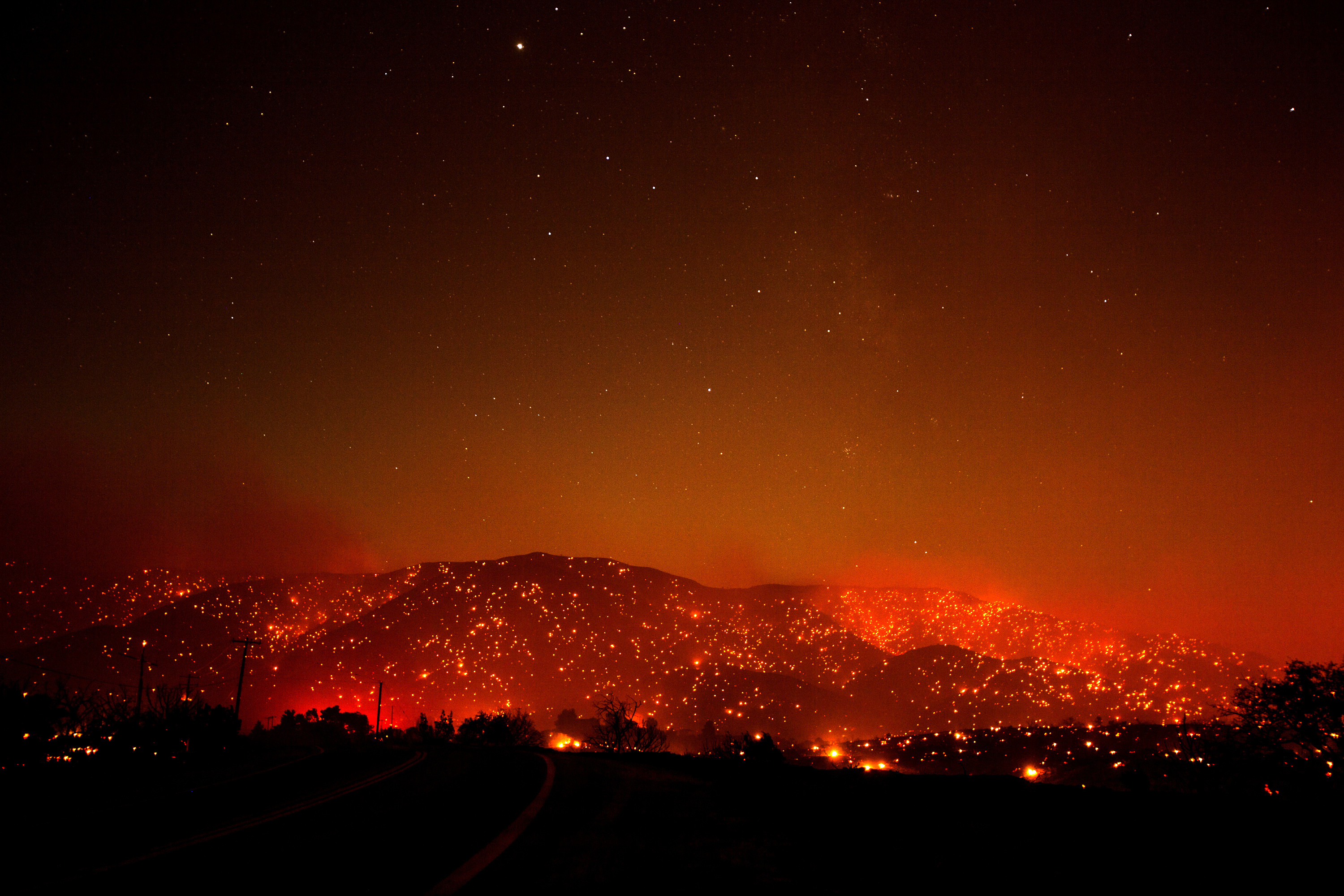 Flames from the Bobcat Fire dot a hill under a glowing smoky sky in Juniper Hills, Calif., Friday, Sept. 18, 2020. (AP Photo/Ringo H.W. Chiu)