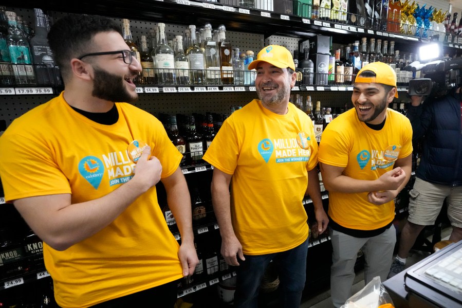 Store co-owner Nidal Khalil, center, smiles with son Jonathan Khalil, left, and nephew Chris Khalil, right, after putting on T-shirts at the Midway Market & Liquor store, Thursday, Oct. 12, 2023, in Frazier Park, Calif., where a winning Powerball lottery ticket was sold. A player in California won a $1.765 billion Powerball jackpot Wednesday night, ending a long stretch without a winner of the top prize. (AP Photo/Marcio Jose Sanchez)