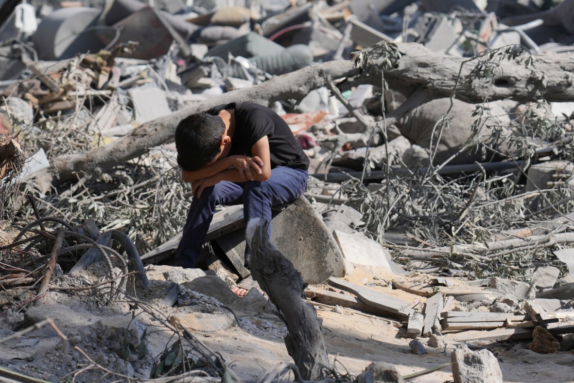 A Palestinian boy sits on the rubble of the building destroyed in an Israeli airstrike in Bureij refugee camp Gaza Strip, Wednesday, Oct. 18, 2023. (AP Photo/Hatem Moussa)