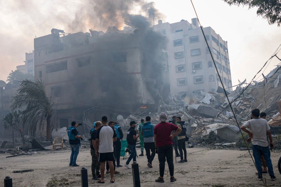 FILE - Journalists observe as Palestinians inspect the rubble of a building after it was struck by an Israeli airstrike, in Gaza City, Sunday, Oct. 8, 2023. Journalists reporting in Gaza need to worry about basic survival for themselves and their families in addition to getting out the story of a besieged population. (AP Photo/Fatima Shbair, File)