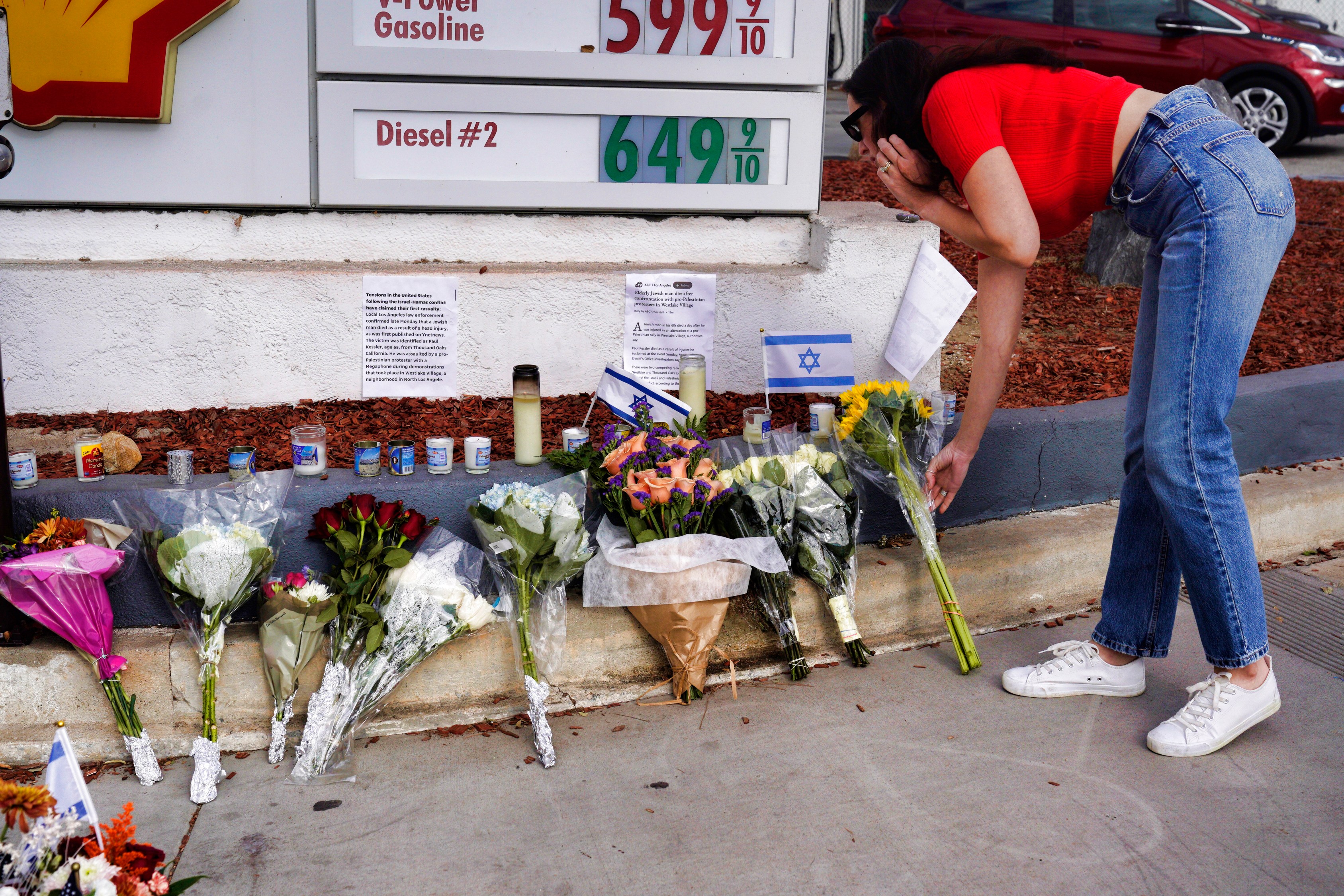 A woman leaves flowers at a makeshift shrine placed at the scene of a Sunday confrontation that lead to death of a demonstrator Tuesday, Nov. 7, 2023, in Thousand Oaks, Calif. Paul Kessler, 69, died at a hospital on Monday from a head injury after witnesses reported he was involved in a "physical altercation" during pro-Israel and pro-Palestinian demonstrations at an intersection in Thousand Oaks, a suburb northwest of Los Angeles, authorities said. (AP Photo/Richard Vogel)