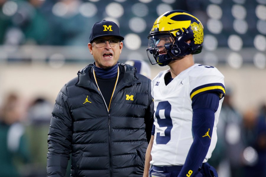 Michigan coach Jim Harbaugh, left, talks to quarterback J.J. McCarthy before an NCAA college football game against Michigan State, Saturday, Oct. 21, 2023, in East Lansing, Mich. (AP Photo/Al Goldis)