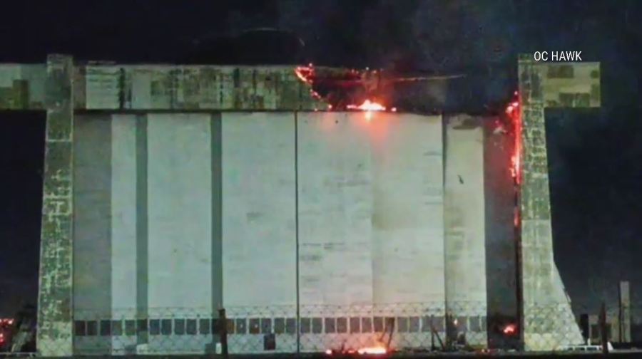 An active flare-up of a fire seen on the doors of a historic airbase hangar in Tustin on Nov. 11 has prompted concerns from residents. (OC Hawk)