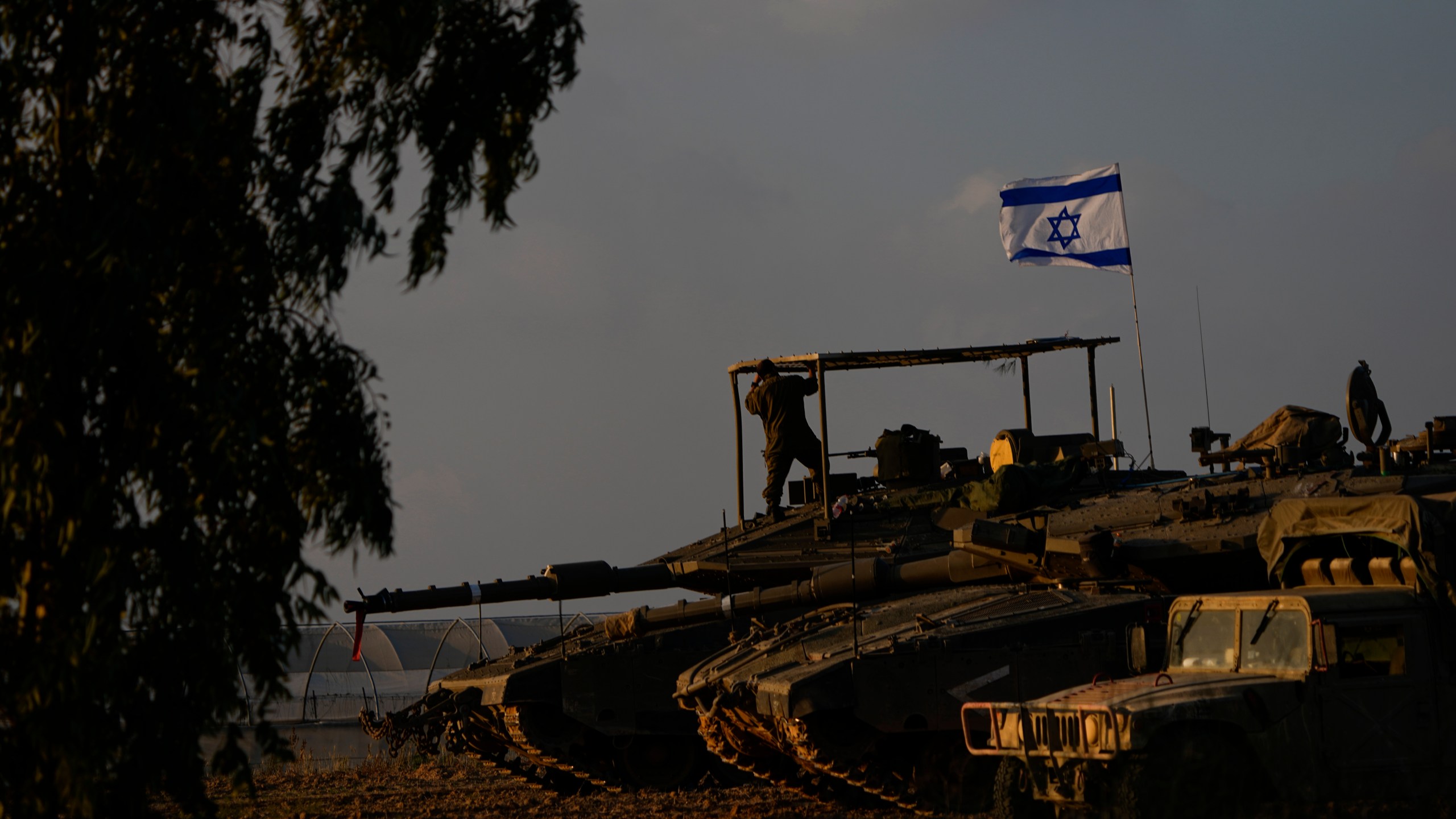 Israeli soldiers work on a tank at an army staging area near Israel's border with Gaza, southern Israel, Friday, Dec. 1, 2023. (AP Photo/Ariel Schalit)