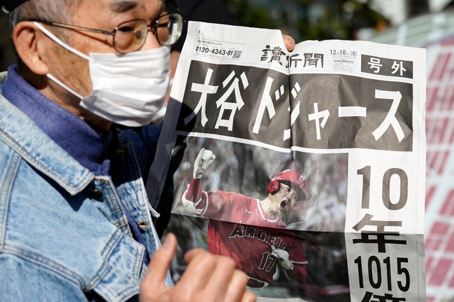 A person reads an extra edition of the Yomiuri Shimbun newspaper reporting on Shohei Ohtani to move to the Los Angeles Dodgers Sunday, Dec. 10, 2023, in Tokyo. Ohtani agreed to a record $700 million, 10-year contract with the Dodgers. (AP Photo/Eugene Hoshiko)