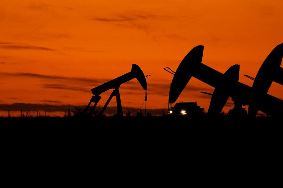 File - A truck passes oil pump jacks at dusk near Karnes City, Texas, Nov. 1, 2023. On Wednesday, the Labor Department releases producer prices data for November. The producer price index is an indicator measuring inflation at the wholesale level, hitting businesses before they pass costs along to consumers. (AP Photo/Eric Gay, File)