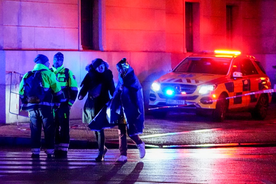 People, one wrapped in a thermal blanket, walk near the building of Philosophical Faculty of Charles University in downtown Prague, Czech Republic, Thursday, Dec. 21, 2023. A mass shooting in downtown Prague killed several people and injured others, and the person who opened fire also is dead, Czech police and the city's rescue service said Thursday. (AP Photo/Petr David Josek)