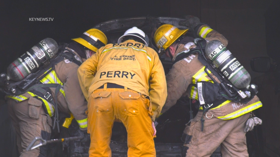 Emergency responders look inside the trunk of a vehicle after responding to a fire in Lancaster.