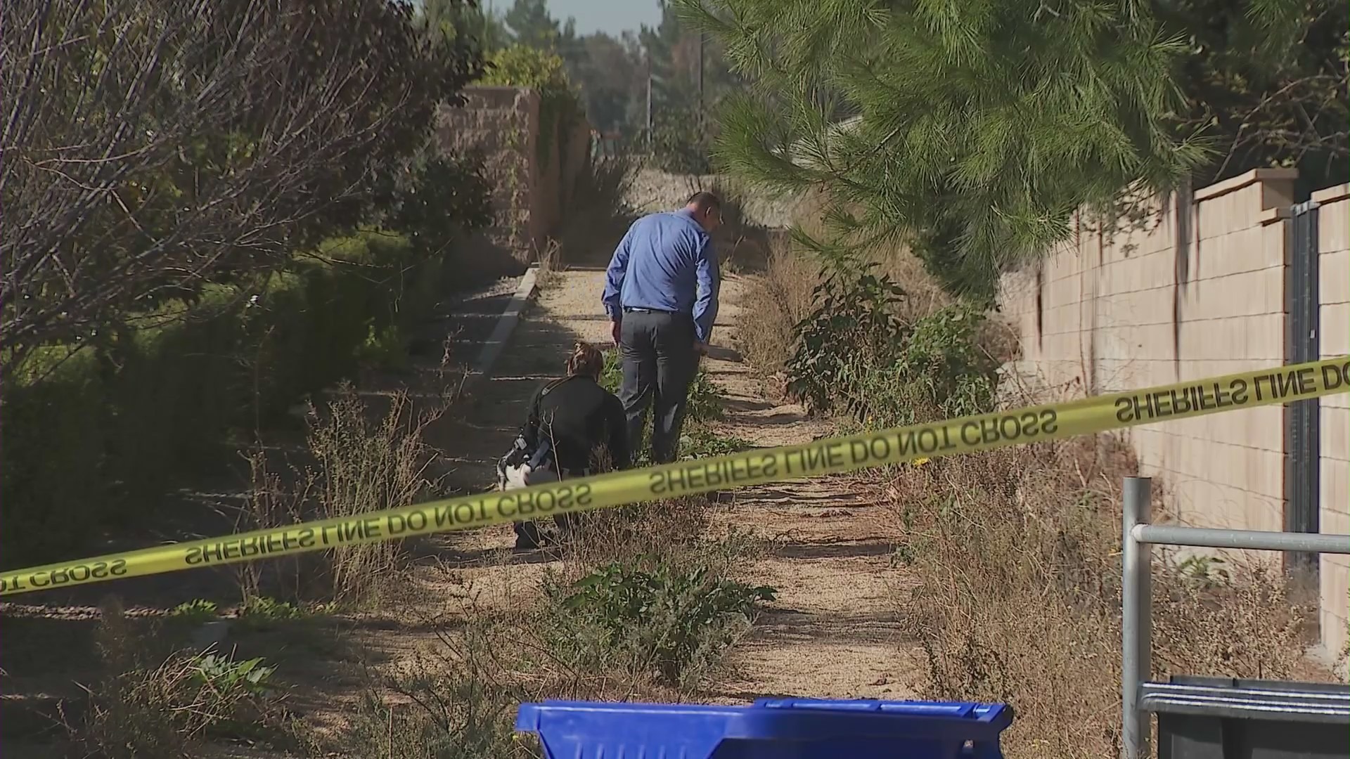 Investigators examine the horse trail next to a home that was used as the escape route by two home invasion suspects on Dec. 12, 2023. (KTLA)