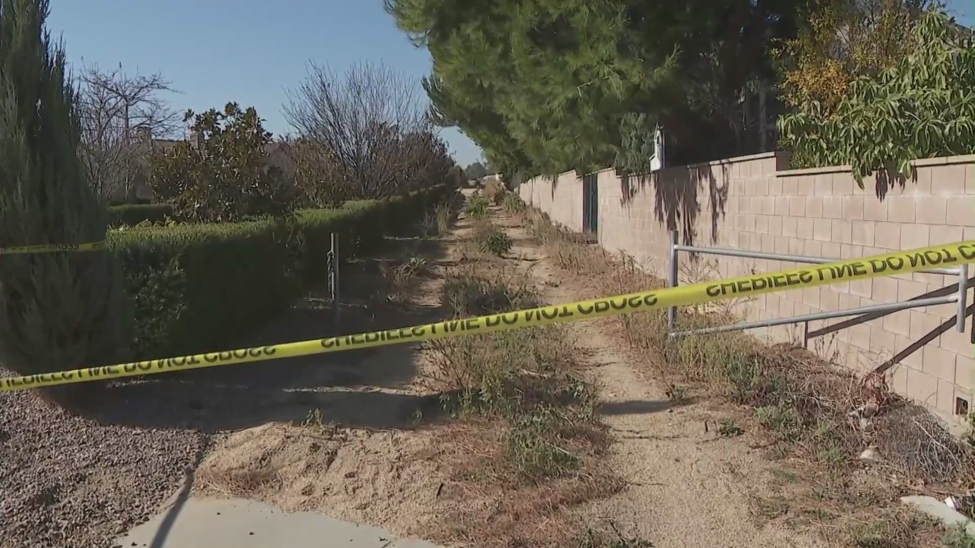 Investigators examine the horse trail next to a home that was used as the escape route by two home invasion suspects on Dec. 12, 2023. (KTLA)