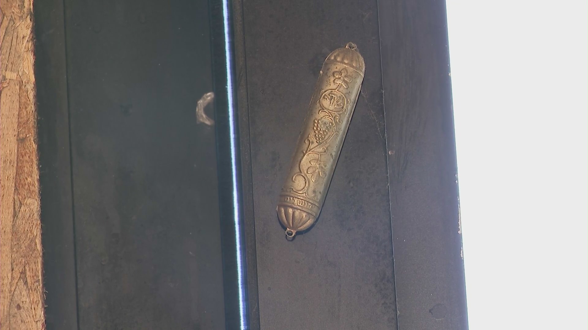 A mezuzah hanging on the door of a vandalized business,