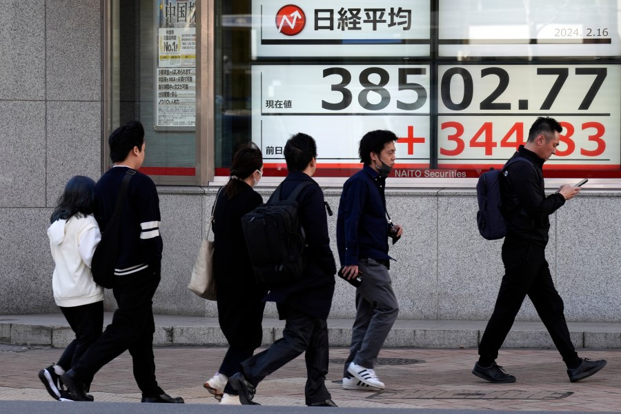 People walk past an electronic stock board showing Japan's Nikkei 225 index at a securities firm Friday, Feb. 16, 2024, in Tokyo. Shares advanced in Asia on Friday, with Tokyo's benchmark Nikkei 225 index trading near a record high, 34 years after it peaked and then plunged with the collapse of Japan's financial bubble. (AP Photo/Eugene Hoshiko)