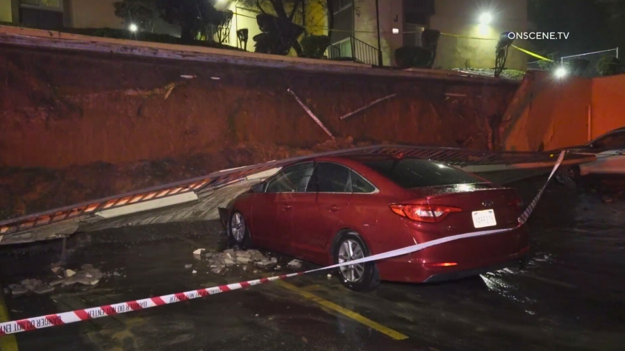 A car is crushed by a retaining wall amid heavy rain in La Habra on Feb. 4, 2024.
