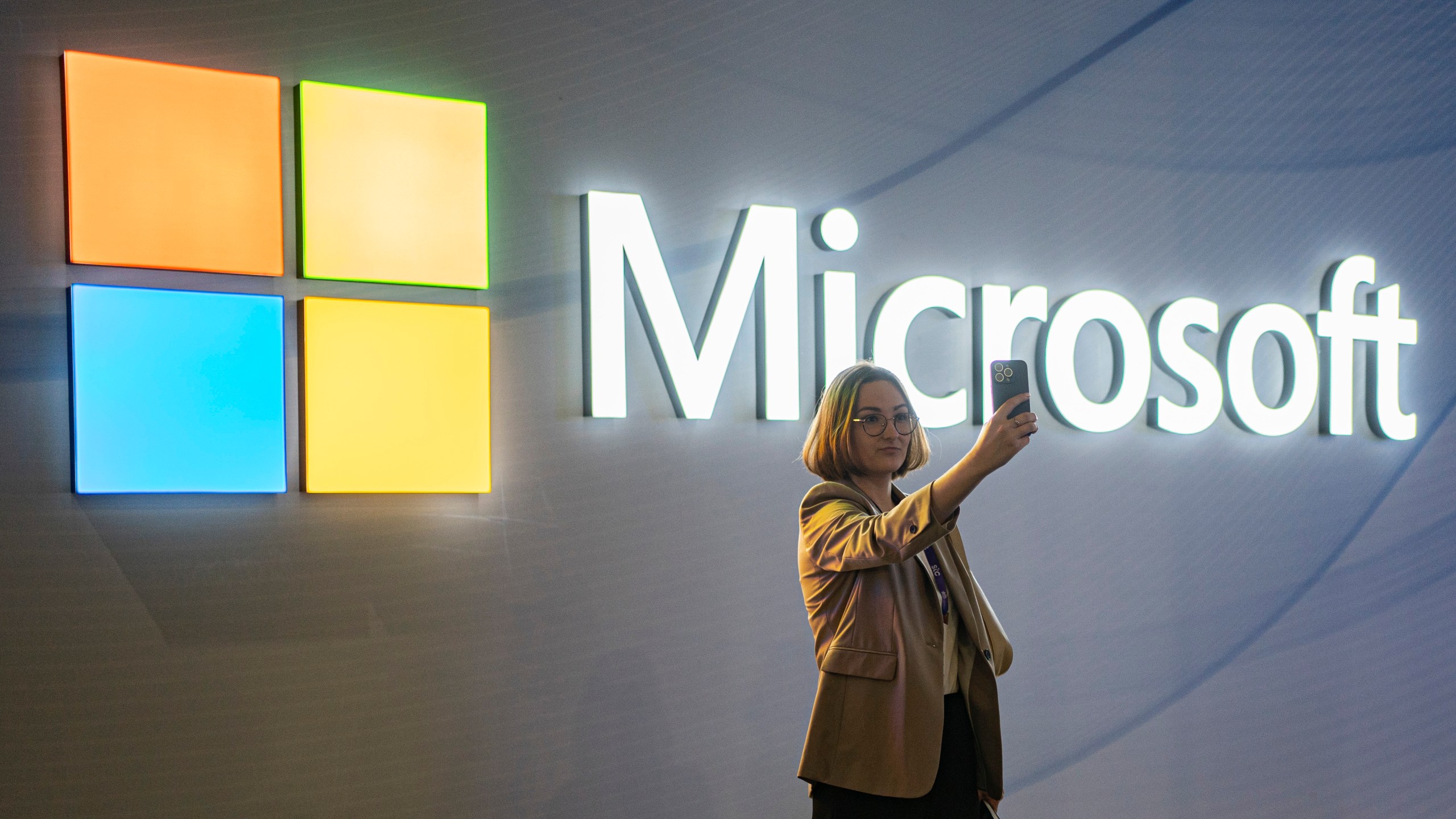 FILE - A visitor takes a photo at the Microsoft stand at Mobile World Congress 2024 in Barcelona, Spain, Feb. 27, 2024. New European Union rules aimed at preventing tech companies from dominating digital markets will change what people see online starting Thursday, March 7, 2024. (AP Photo/Pau Venteo, File)