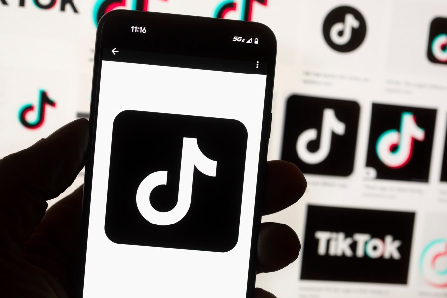 FILE - The TikTok logo is seen on a mobile phone in front of a computer screen which displays the TikTok home screen, Oct. 14, 2022, in Boston. Lawmakers in Georgia, early Friday, March 29, 2024, approved a bill that would require parental permission before children younger than 16 could sign up for social media accounts. (AP Photo/Michael Dwyer, File)