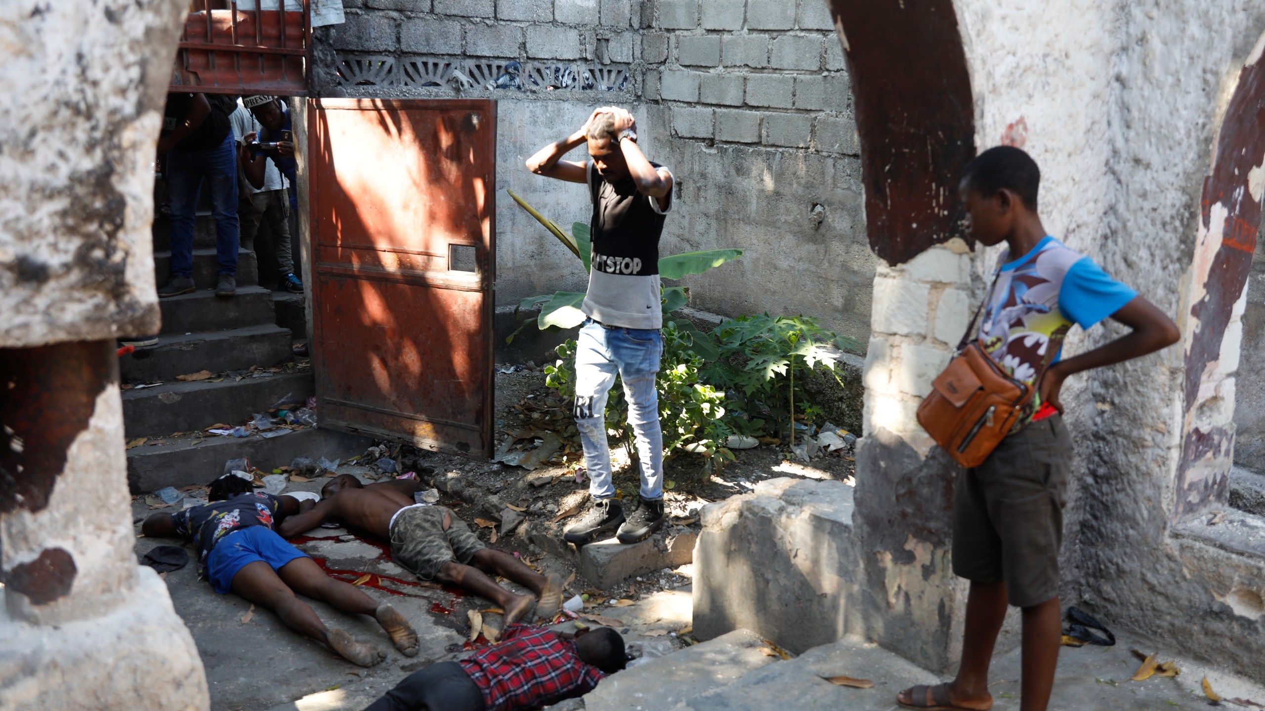 People look at the the bodies of three persons shot dead after an overnight shooting in the Pétion Ville neighborhood of Port-au-Prince, Haiti, Monday, April 1, 2024.(AP Photo/Odelyn Joseph)