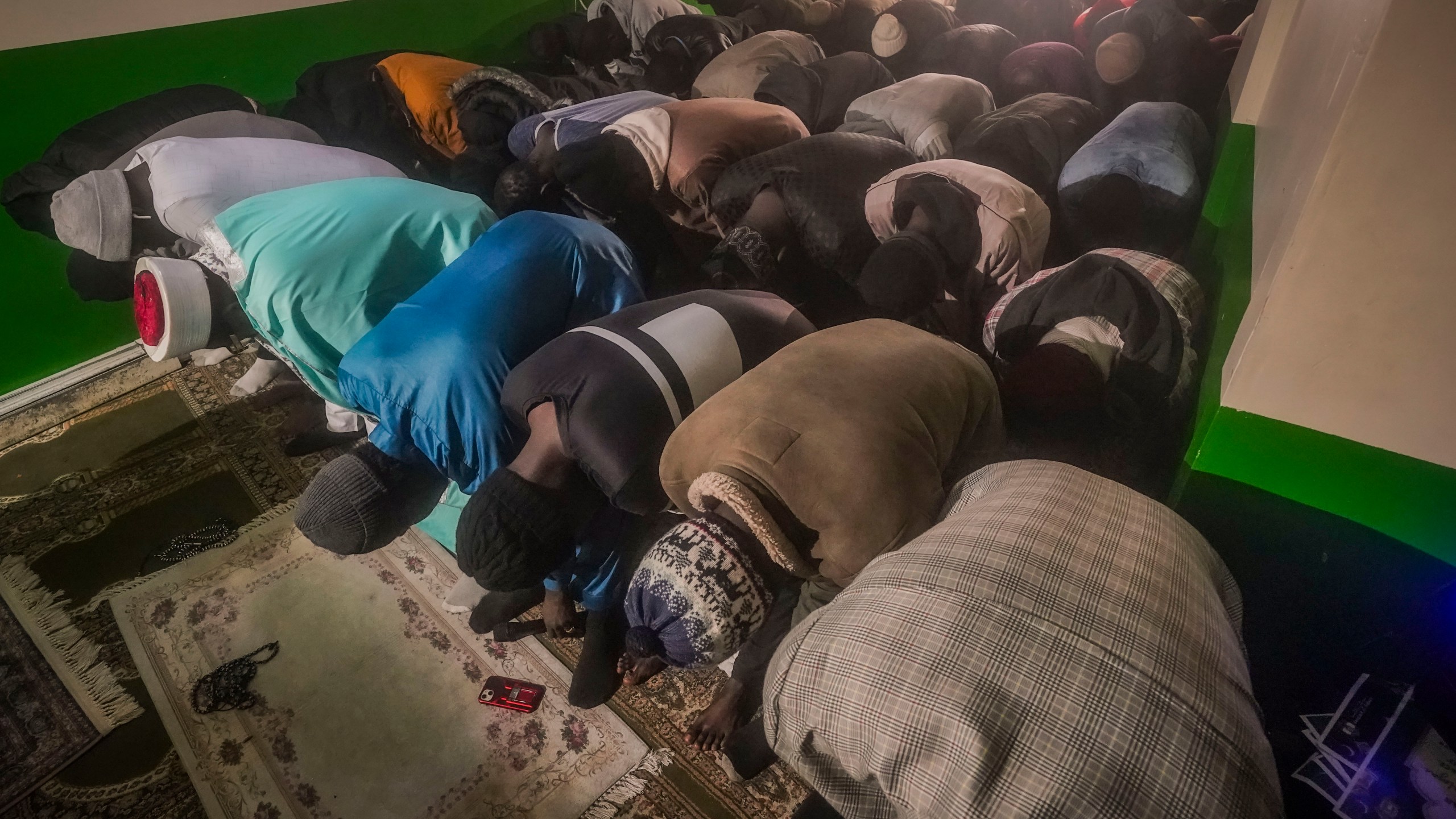 Imam Omar Niass, third from left top, lead evening prayers for African migrants, before the breaking of Ramadan fast and the serving of a festive meal called an iftar, Friday March 15, 2024, at Bronx's Masjid Ansaru-Deen mosque in New York. The mosque, formerly the family home for Imam Niass, has been a refuge since 2020 for African migrants seeking asylum in the United States.(AP Photo/Bebeto Matthews)