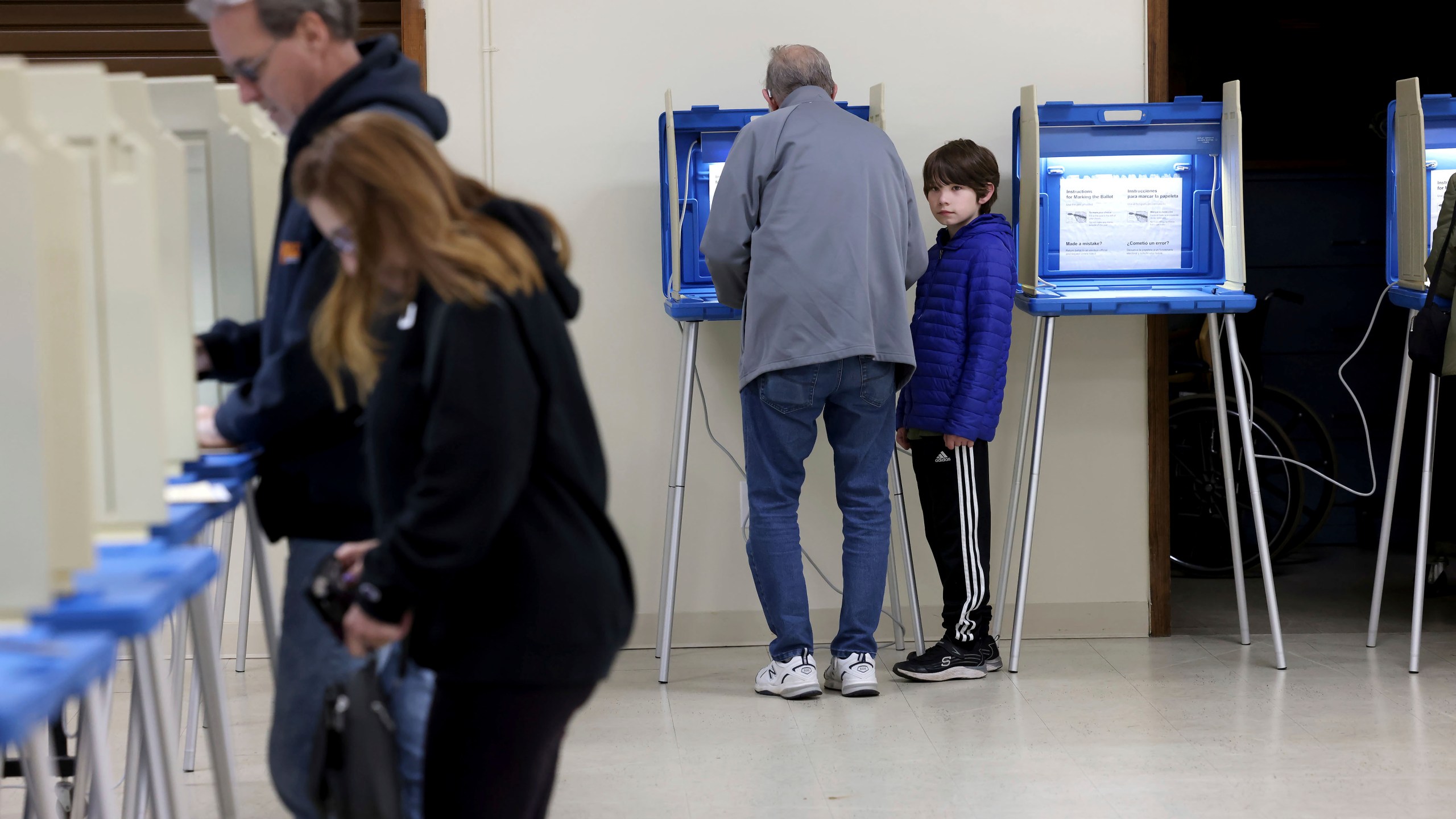 Arthur Crookes, center, fills out his ballot as his grandson, Joseph Godek, 9, right, watches at a polling station in Cumberland, R.I. during the state's primary election, Tuesday, April 2, 2024. Rhode Island is one of four states holding primary elections on Tuesday. (AP Photo/Mark Stockwell)