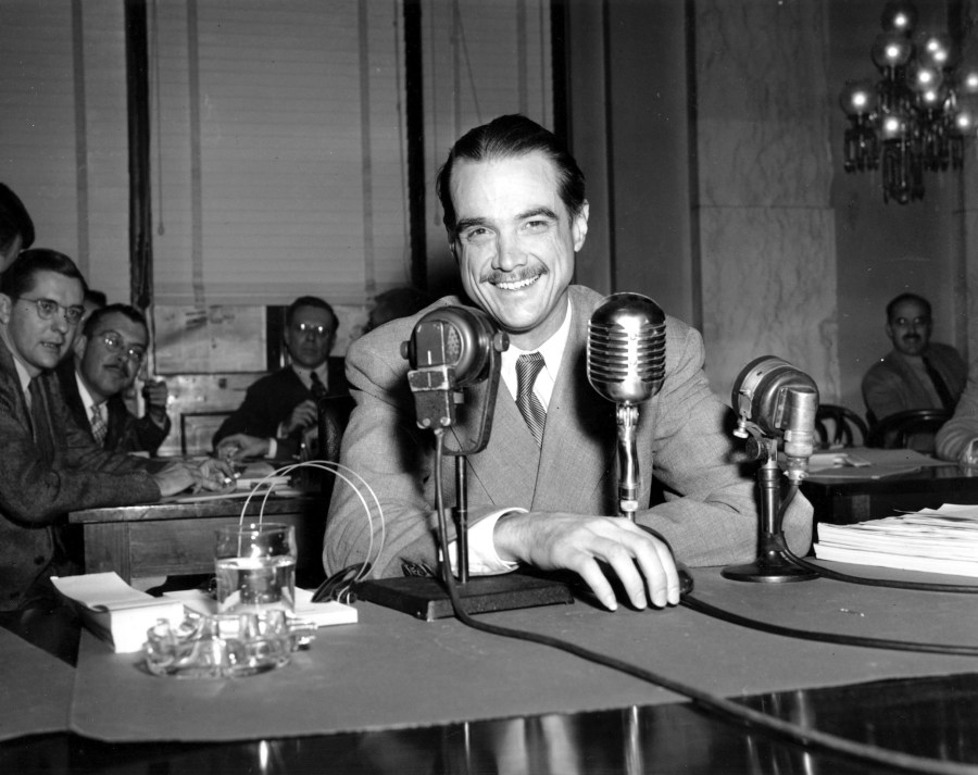 FILE - Howard Hughes smiles as he sits in the witness chair before reading a statement at the Senate War Investigation Subcommittee hearing in Washington, Nov. 15, 1947. Hughes played a supporting role in the CIA’s effort to retrieve part of a sunken Soviet submarine in 1974 with a specialized ship that was built to retrieve the sub and was called the Hughes Glomar Explorer. (AP Photo/File)