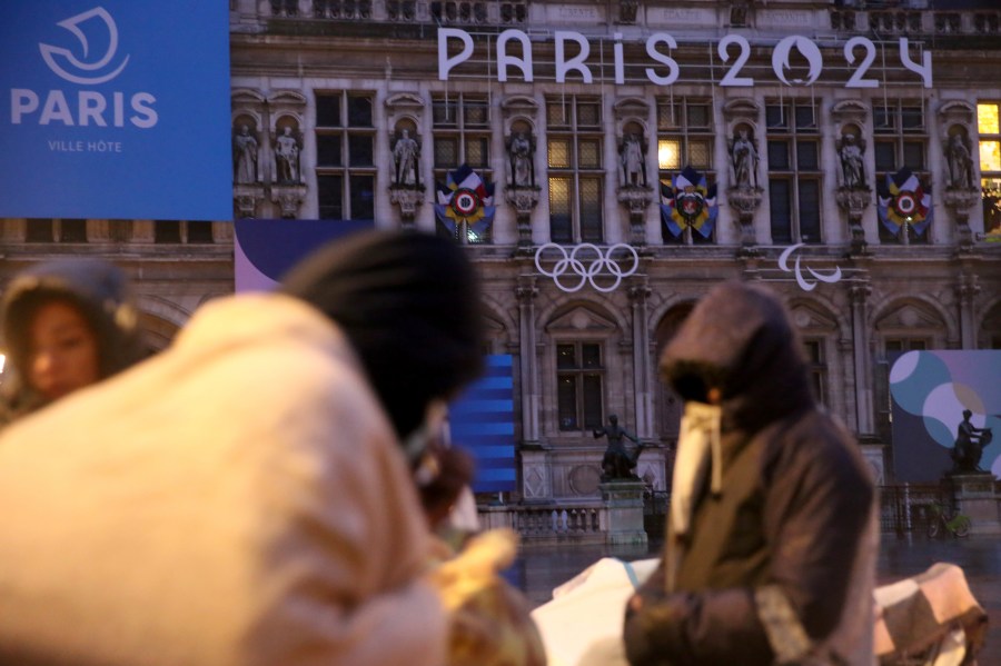 Migrants stand in front of the Paris City Hall, Wednesday, April 3, 2024. French police has removed about 50 migrants, including families with young children, from the Paris City Hall plaza as the capital prepares to mark 100 days to the start of the Olympic Games. (AP Photo/Nicolas Garriga)