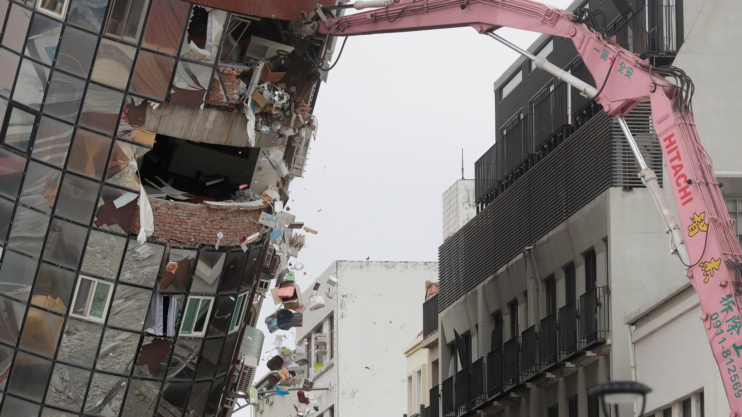 Heavy equipment begins demolition of a collapsed building, two days after a powerful earthquake struck the city, in Hualien City, eastern Taiwan, Friday, April 5, 2024. (AP Photo/Chiang Ying-ying)