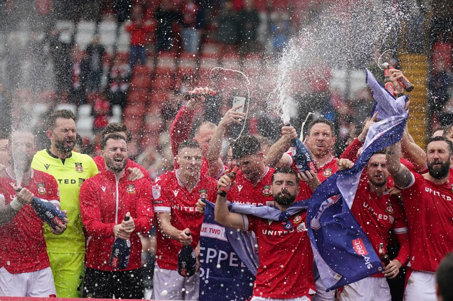 Wrexham players on the pitch celebrate promotion to League One after the final whistle of the Sky Bet League Two match at the SToK Cae Ras, Wrexham, Saturday April 13, 2024. (Jacob King/PA via AP)