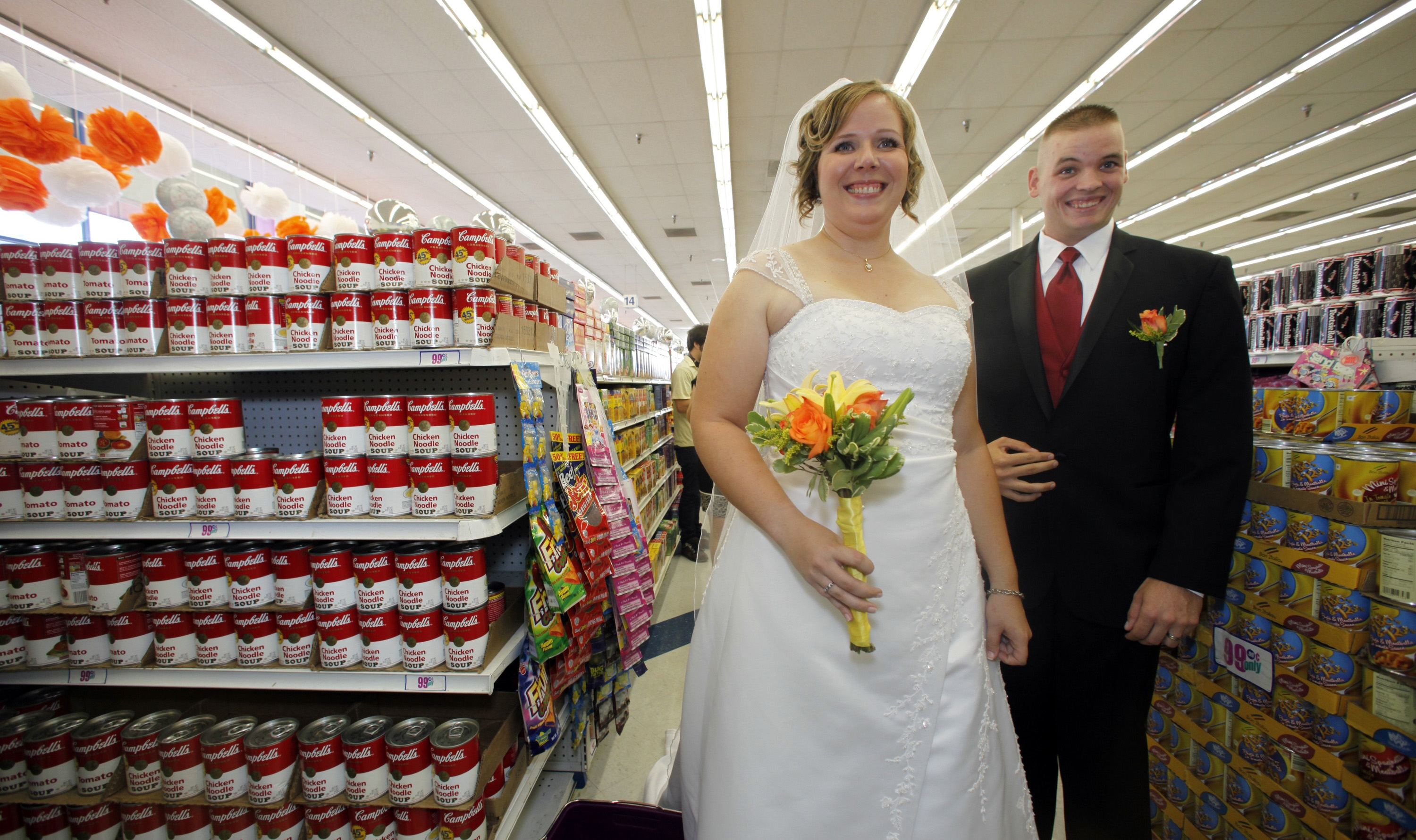 US Marine Whillis Hall, Jr. right, and bride Emily Wiley, react after getting married along other nine couples at the 99 Cent store in the Hollywood section of Los Angeles on Wednesday, Sep. 09, 2009. The discount chain will send the couples off in a limousine, with $99.99 in cash, and take them to an undisclosed "famous romantic Los Angeles" spot. All nine couples who got married in the store also will get a free night's stay, including dinner, at the Hotel Angeleno. (AP Photo/Damian Dovarganes)