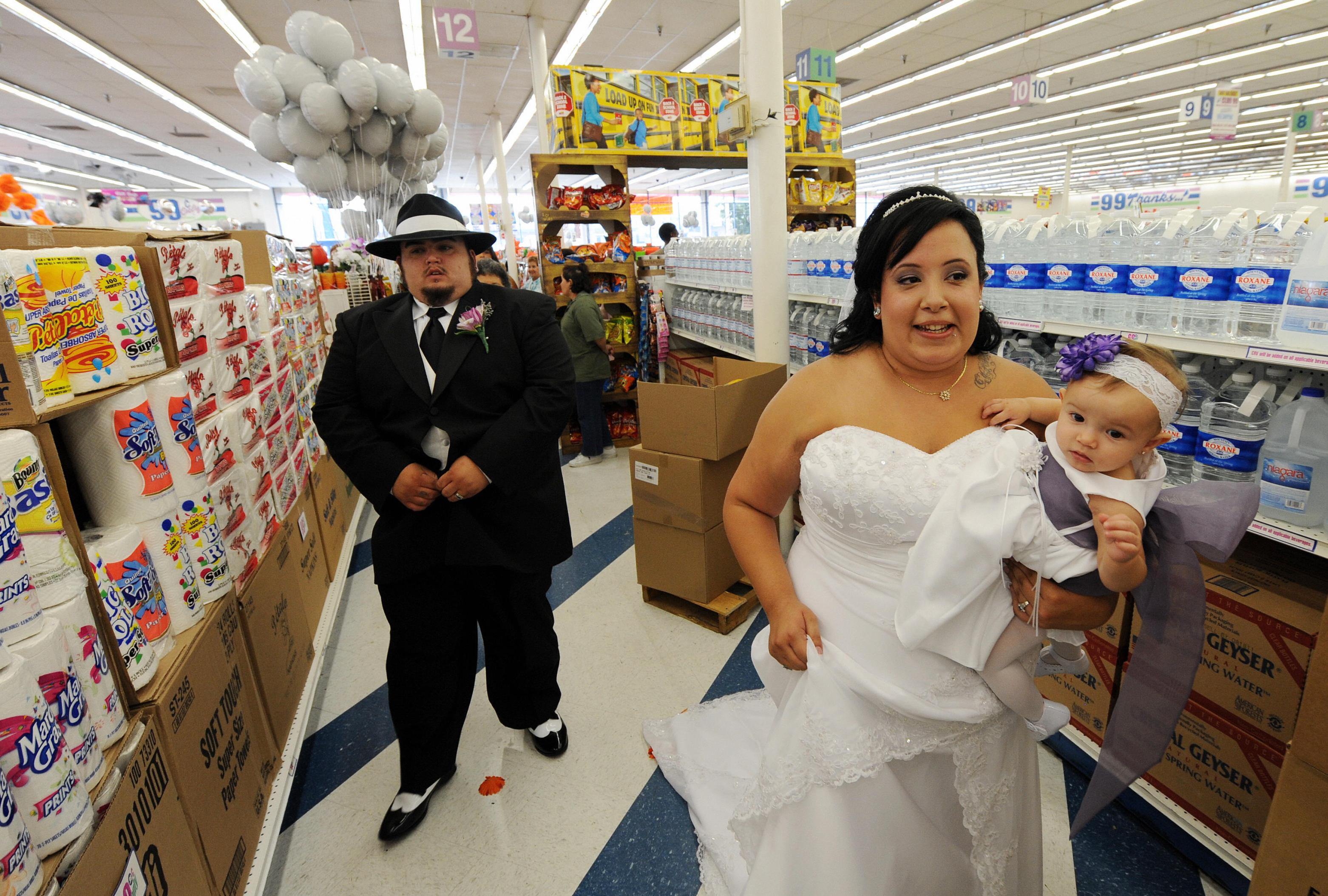 Lesley Barragan and John Tinker walk down food aisles before their 99 cent wedding ceremony at the 99 cent store in Los Angeles on September 9, 2009. The budget supermarket chain helped nine happy California couples beat the recession blues by offering cut-price wedding ceremonies -- for just 99 cents each. The 99 Cents Only Stores chain is picking up the tab for nine couples at its branch on Sunset Boulevard in the heart of Hollywood on Wednesday to mark the ninth day of the nine month in 2009. After getting hitched, the nine couples were handed 99 dollars and 99 cents in cash before being whisked off to an undisclosed "famous romantic Los Angeles" location. AFP PHOTO/Mark RALSTON (Photo credit should read MARK RALSTON/AFP via Getty Images)