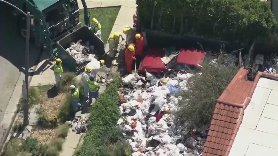 Crews began clearing mountains of trash and debris seen in the front yard of a Fairfax home in Los Angeles on April 3, 2024. (KTLA)