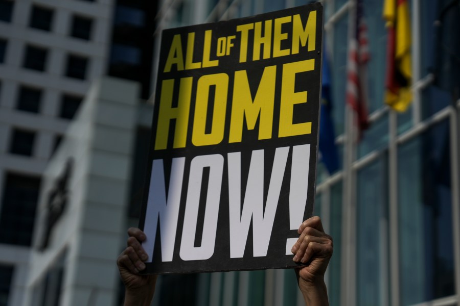 A woman holds a banner with families and supporters of Israeli hostages held by Hamas in Gaza during a protest calling for their return, outside a meeting between U.S. Secretary of State Antony Blinken and families of hostages in Tel Aviv, Israel, Wednesday, May 1, 2024. (AP Photo/Oded Balilty)