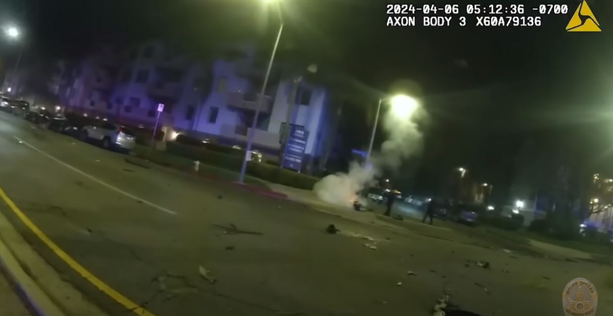 Officers work to extinguish large pieces of smoking auto debris strew across the roadway. (Los Angeles Police Department)