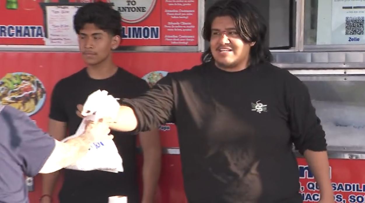 Erick Flores and a coworker outside of the Los Bros Tacos truck in Long Beach, California. (KTLA)