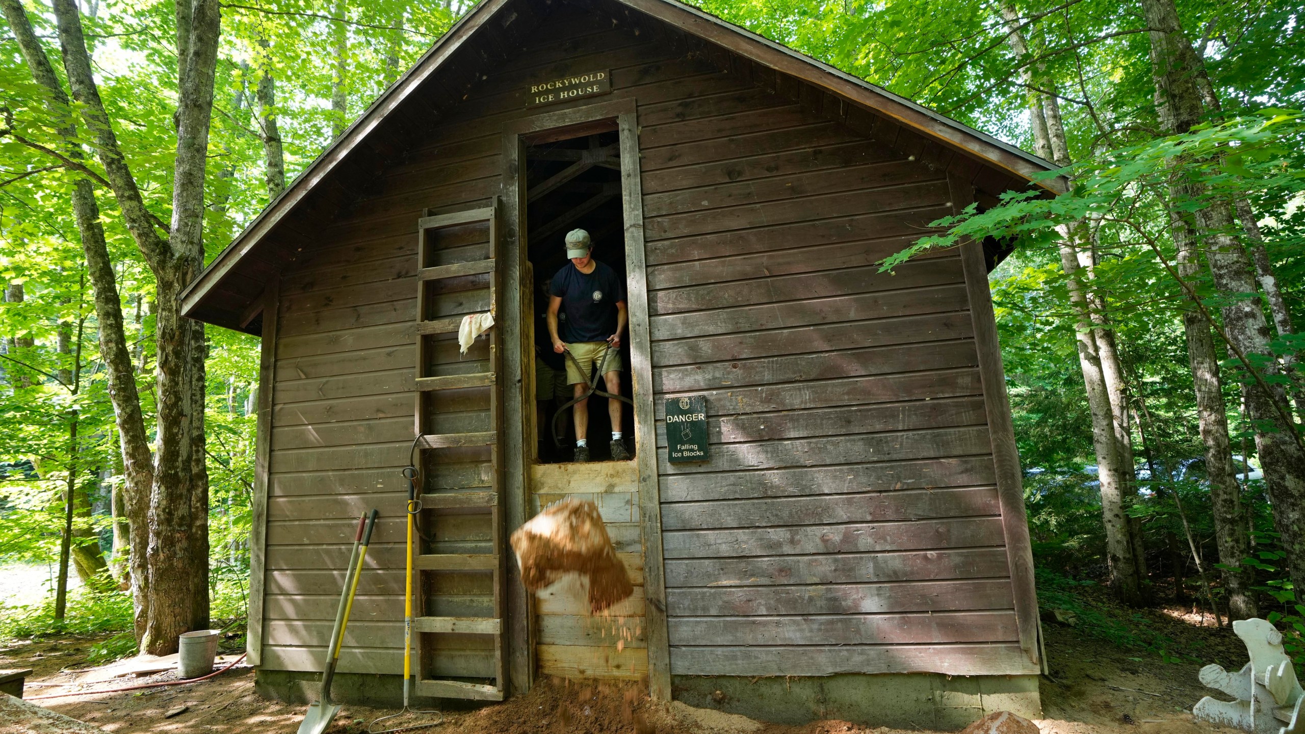 Travis Miller drops a block of ice from one of two ice houses at Rockywold Deephaven Camps, Thursday, June 20, 2024, in Holderness, N.H. (AP Photo/Robert F. Bukaty)