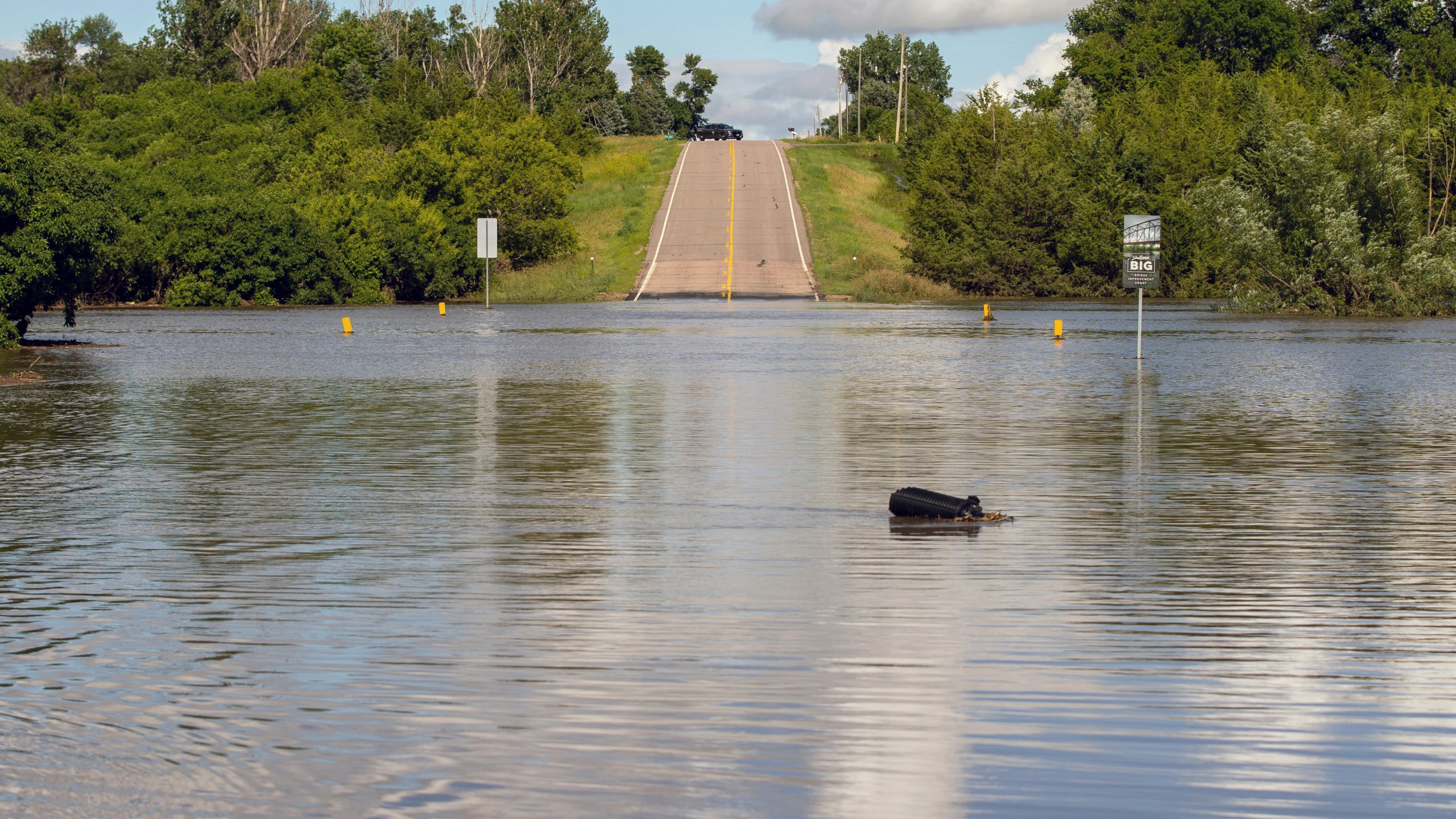 A South Dakota Highway Patrol Officer keeps watch over a flooded bridge that was underwater after days of heavy rain led to flooding in the area, near Lake Alvin, S.D., Saturday, June 22, 2024. (AP Photo/Josh Jurgens)