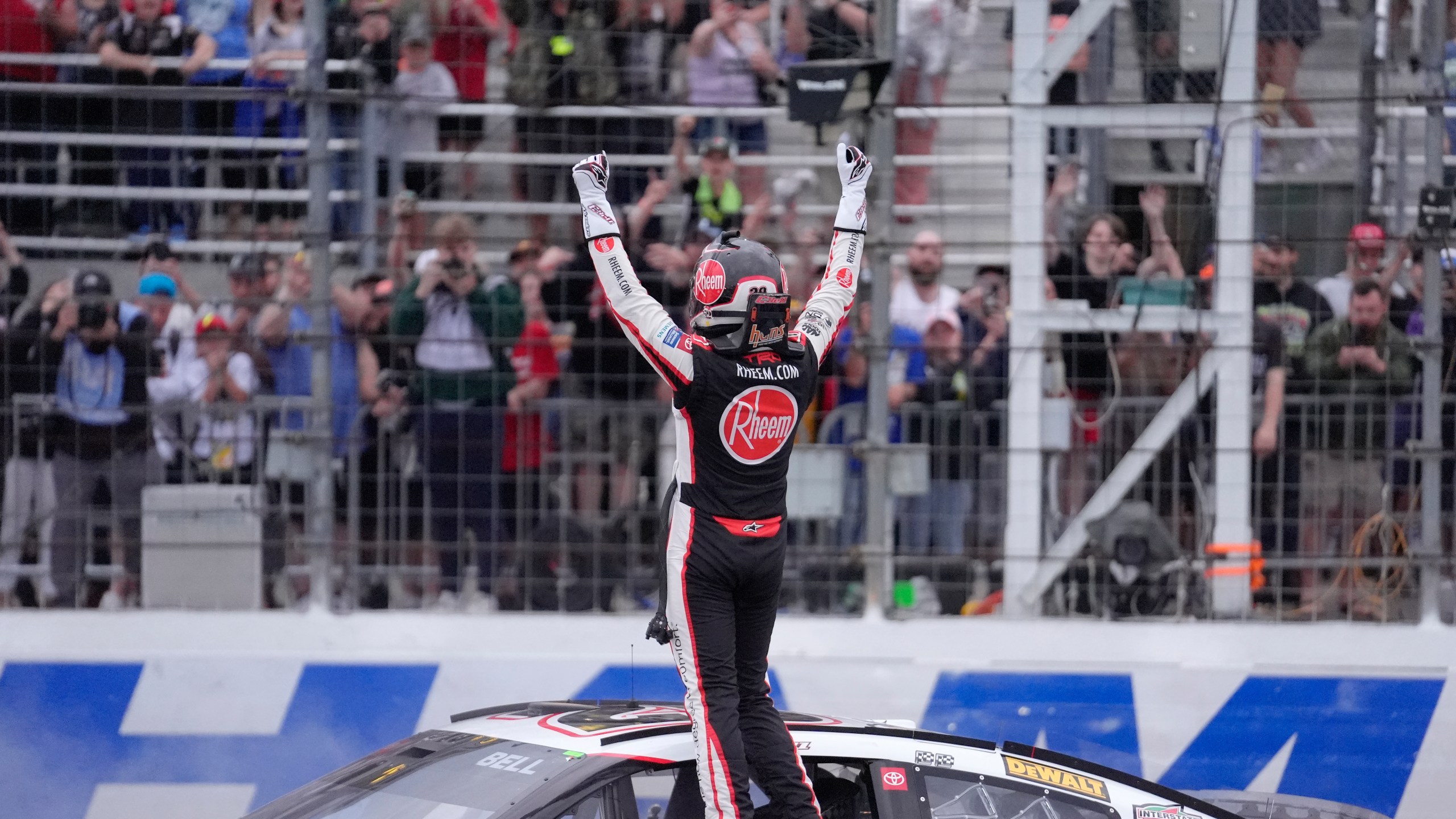 Christopher Bell raises his arms as he faces the crowd after winning the NASCAR Cup Series race at New Hampshire Motor Speedway, Sunday, June 23, 2024, in Loudon, N.H. (AP Photo/Steven Senne)