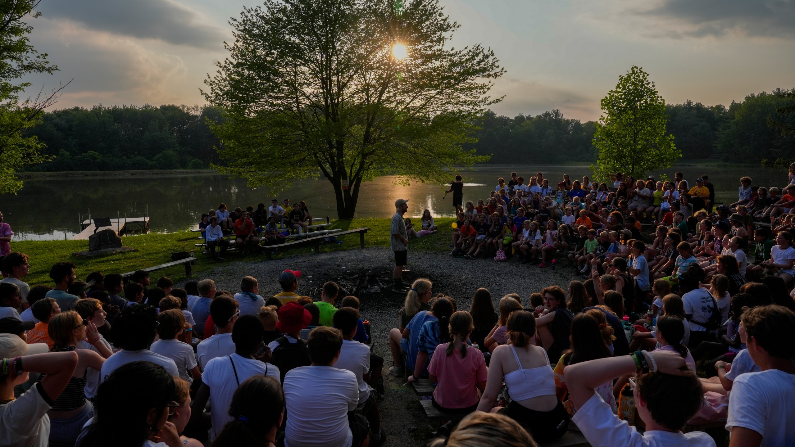 Counselors perform a camp song during closing campfire, Thursday, June 20, 2024, at YMCA Camp Kern in Oregonia, Ohio. As the first heat wave of the season ripples across the U.S., summer camps are working to keep their children cool while still letting the kids enjoy being outside with nature. (AP Photo/Joshua A. Bickel)