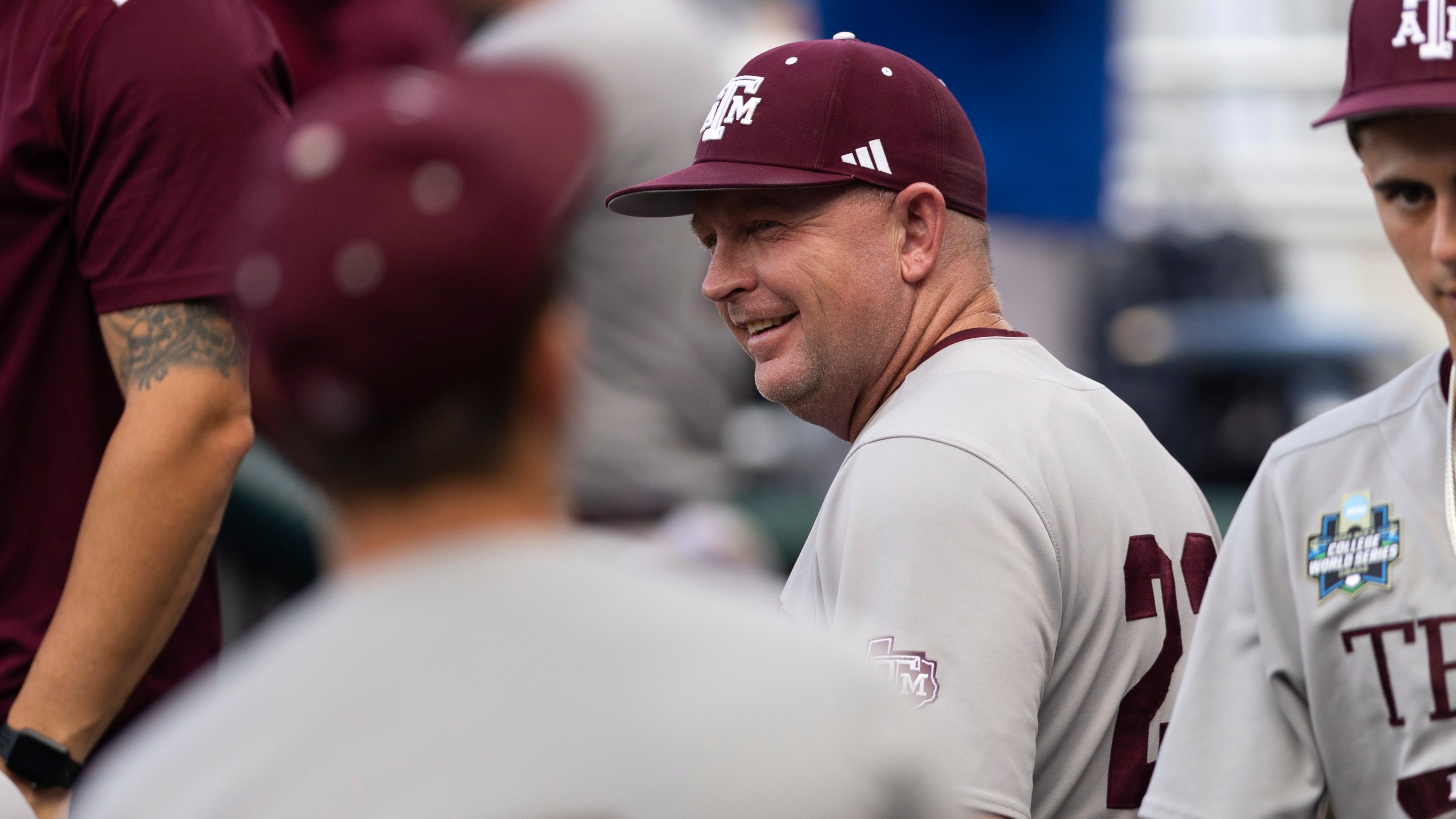 Texas A&M coach Jim Schlossnagle smiles in the dugout before his team plays against Tennessee in Game 1 of the NCAA College World Series baseball finals in Omaha, Neb., Saturday, June 22, 2024. (AP Photo/Rebecca S. Gratz)