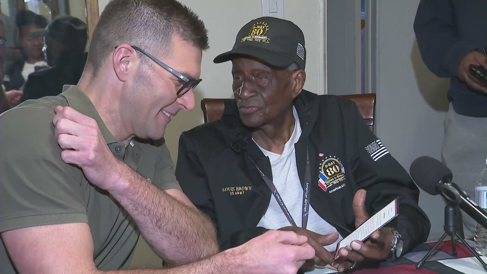 Louis Brown sharing photos of his time in the Army during World War II with KTLA's John Fenoglio. (KTLA)