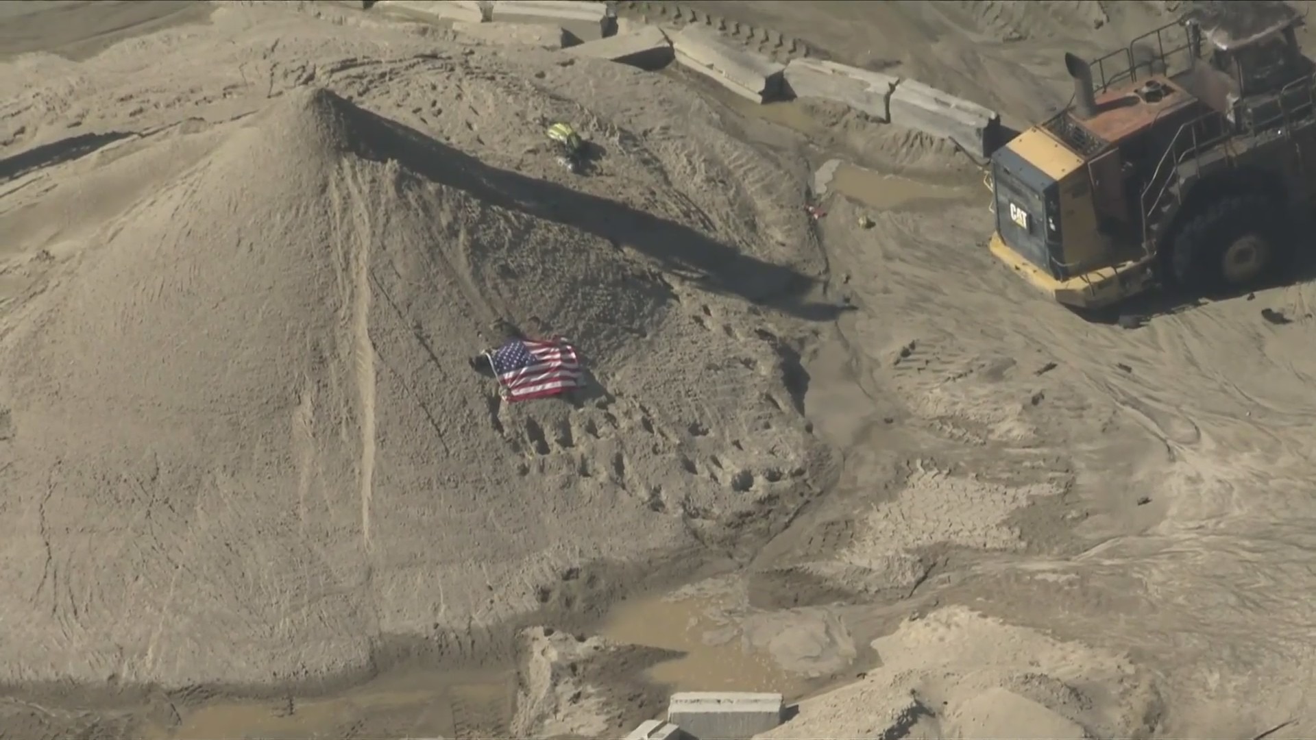 A body was seen covered by an American flag after a deadly explosion near Palmdale on June 14, 2024. (KTLA)