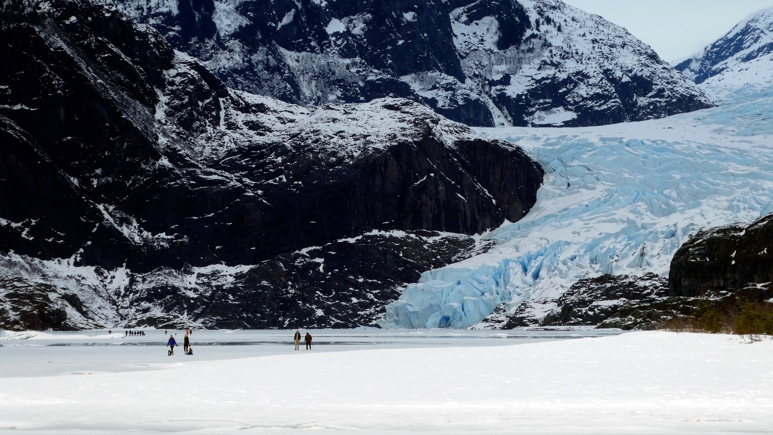 FILE - People walk on a frozen Mendenhall Lake, with Mendenhall Glacier in the background, Feb. 18, 2024, in Juneau, Alaska. A new study says the melting of Alaska’s Juneau icefield, home to more than 1,000 glaciers, is accelerating. (AP Photo/Becky Bohrer, File)