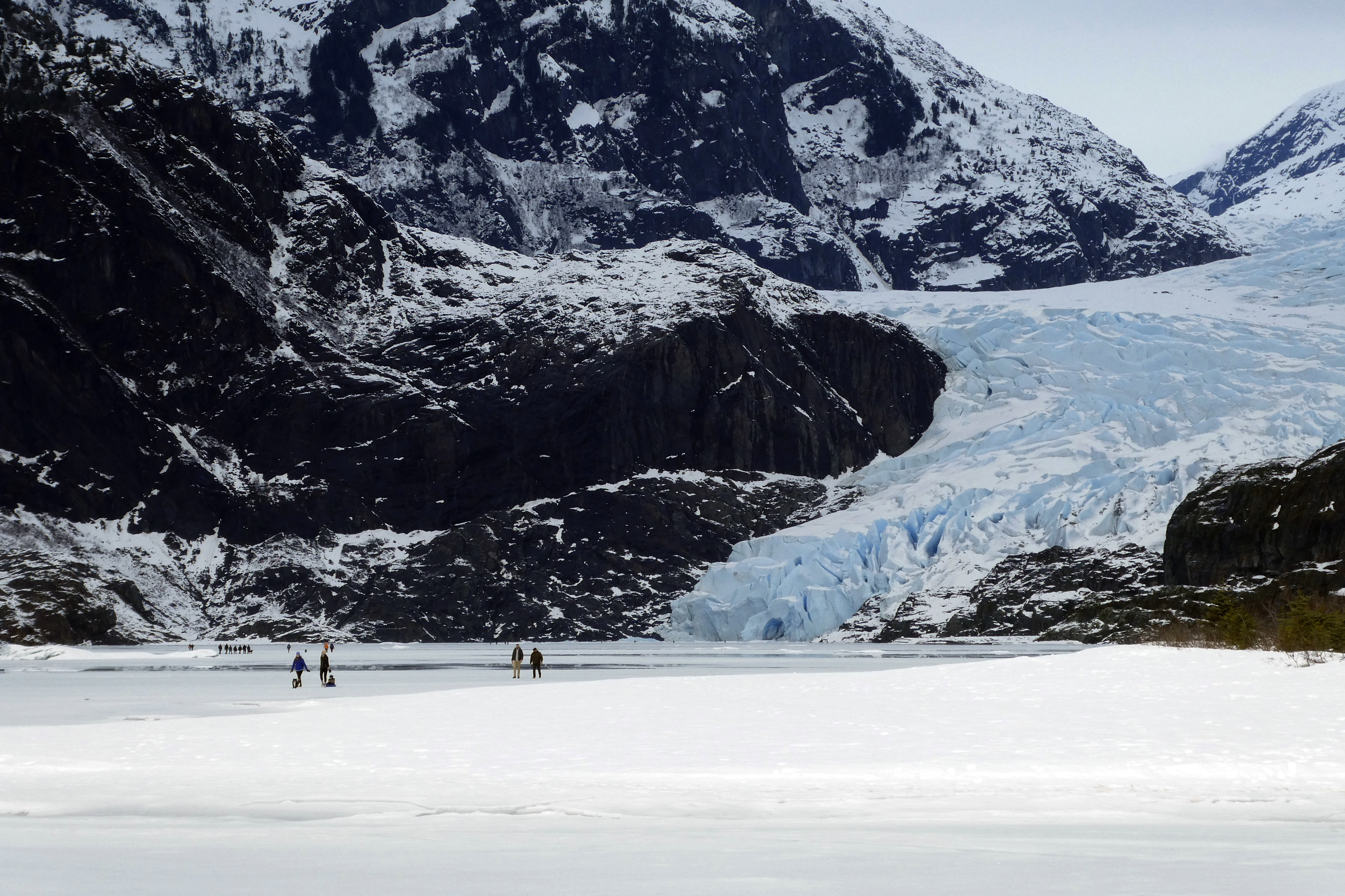 FILE - People walk on a frozen Mendenhall Lake, with Mendenhall Glacier in the background, Feb. 18, 2024, in Juneau, Alaska. A new study says the melting of Alaska’s Juneau icefield, home to more than 1,000 glaciers, is accelerating. (AP Photo/Becky Bohrer, File)