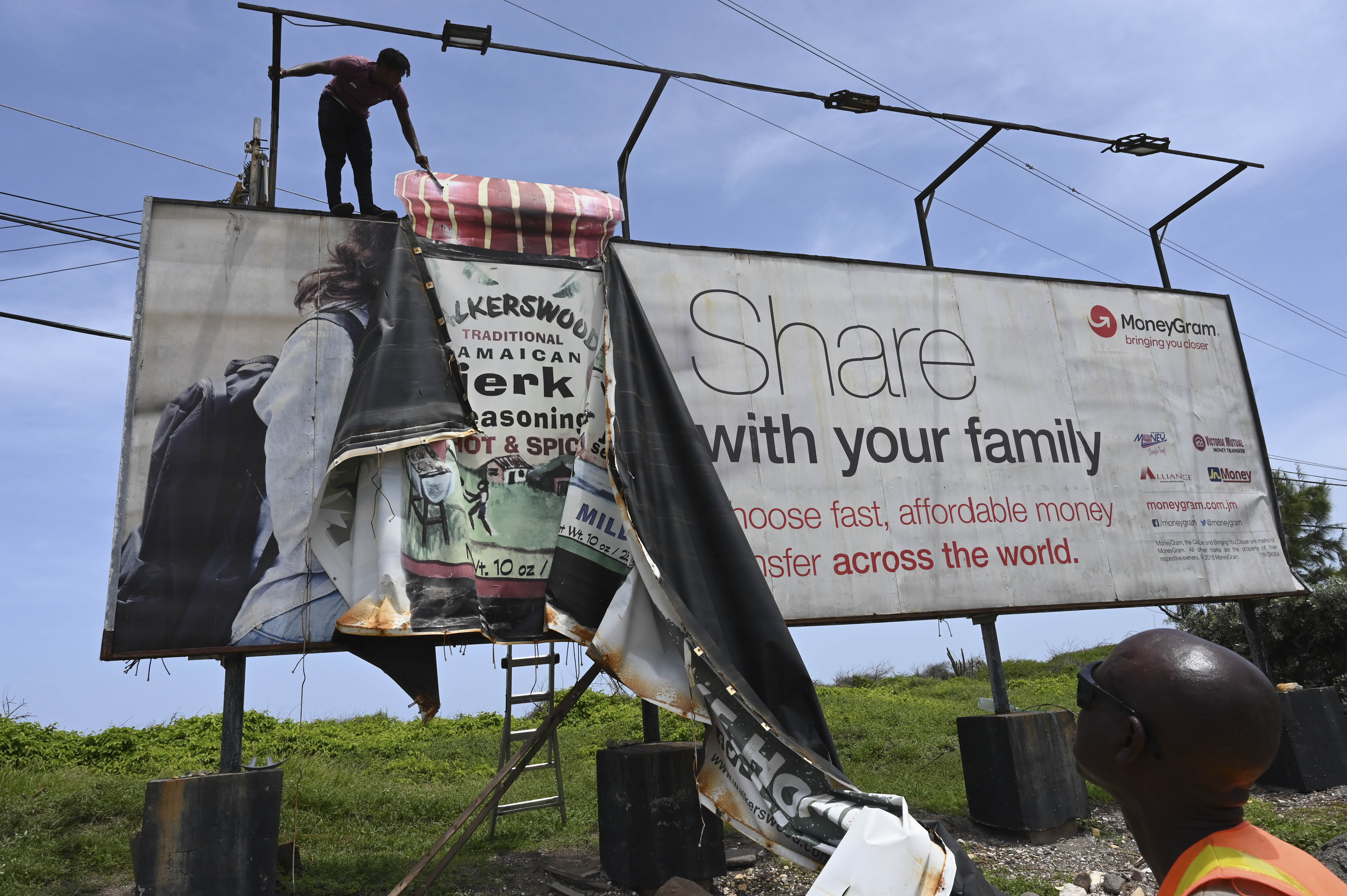 Workers dismantle an advertisement board to protect it from Hurricane Beryl in Kingston, Jamaica, Tuesday, July 2, 2024. (AP Photo/Collin Reid)