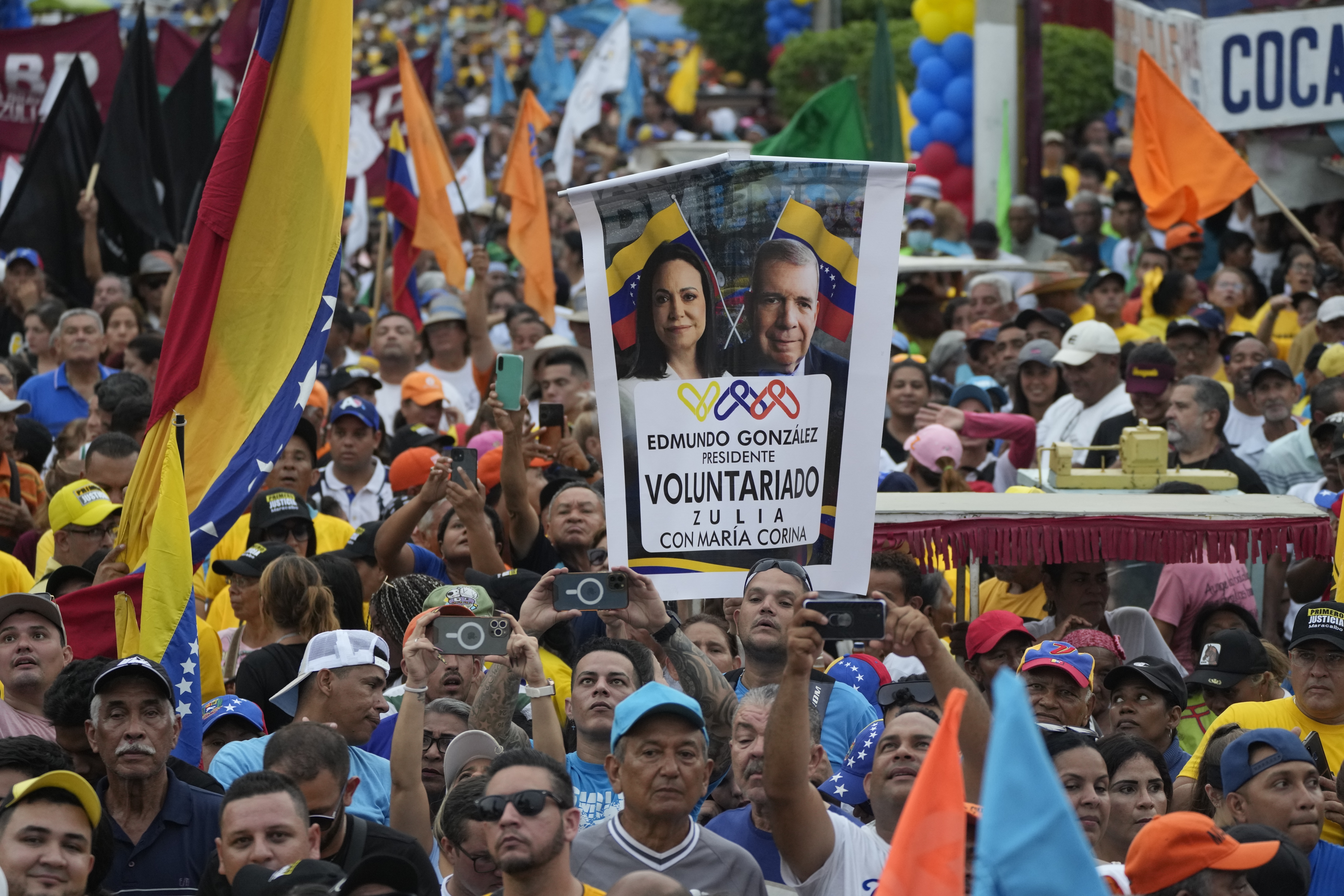 FILE - A supporter holds up a banner with images of opposition leader Maria Corina Machado and presidential candidate Edmundo Gonzalez, during a campaign rally in Maracaibo, Venezuela Thursday, May 2, 2024. No decision in Venezuela over the past 25 years has been as consequential as the choice voters will make on July 28. (AP Photo/Ariana Cubillos, File)