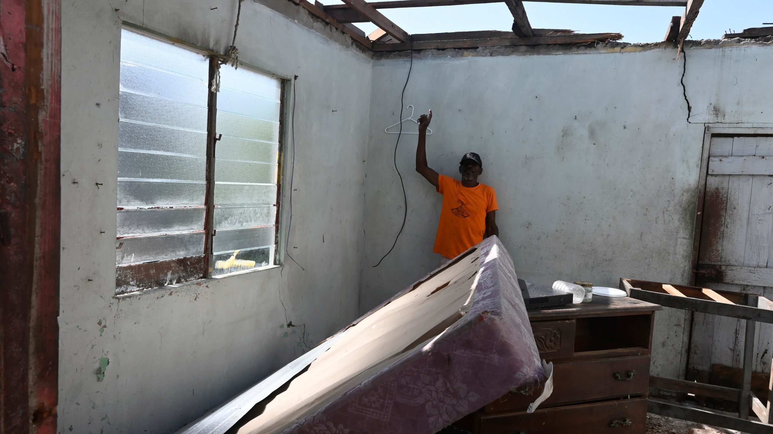 A man shows the destroyed roof of his home from Hurricane Beryl in the fishing settlement of Rocky Point, Clarendon, Jamaica, Thursday, July 4, 2024. (AP Photo/Collin Reid)