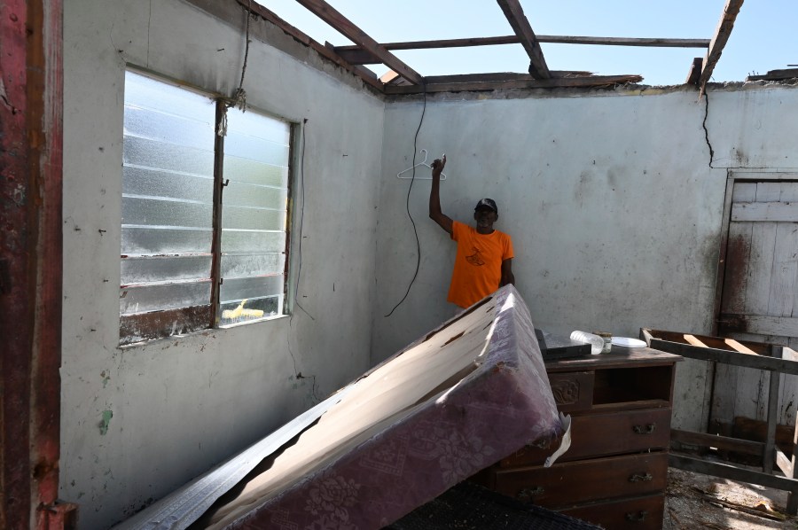 A man shows the destroyed roof of his home from Hurricane Beryl in the fishing settlement of Rocky Point, Clarendon, Jamaica, Thursday, July 4, 2024. (AP Photo/Collin Reid)