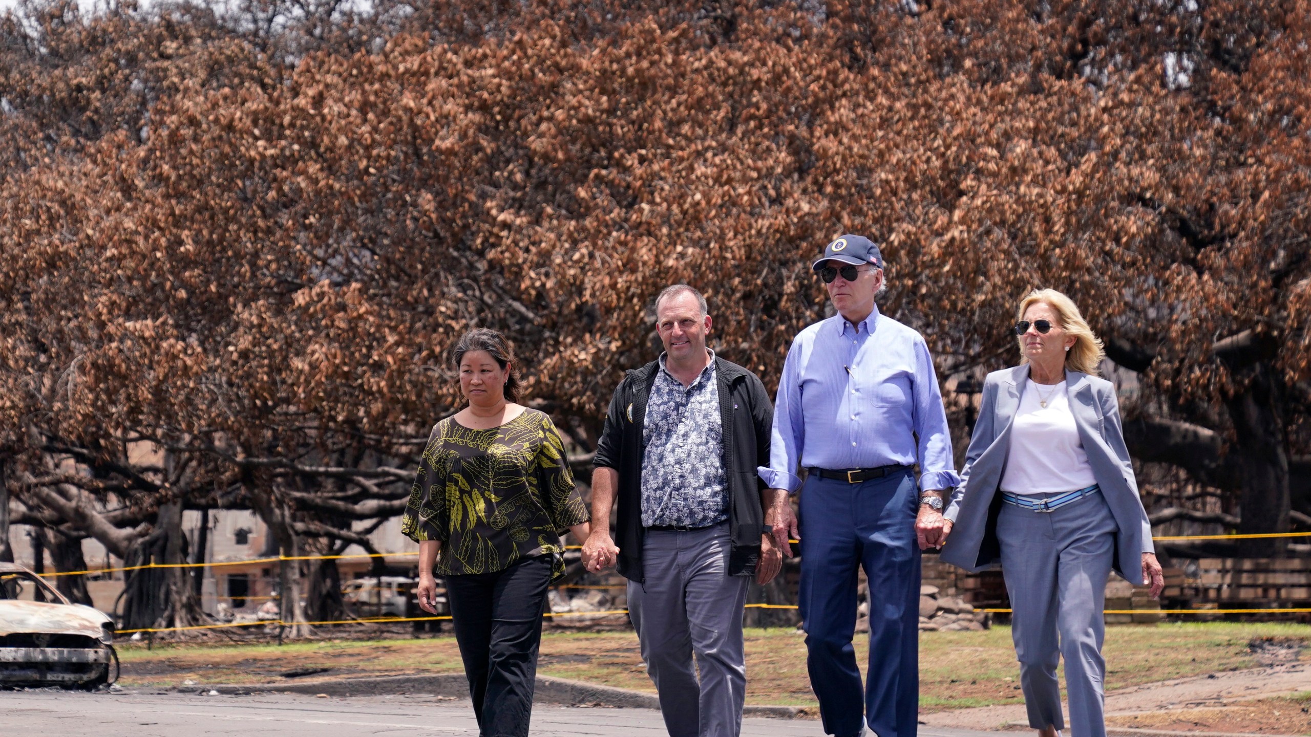 FILE - President Joe Biden and first lady Jill Biden walk with Hawaii Gov. Josh Green, second from left, and his wife Jaime Green as they pass the massive Banyan tree while visiting areas devastated by the Maui wildfires, Aug. 21, 2023, in Lahaina, Hawaii. Green, on Saturday, July 6, 2024, said Biden could decide within days whether to remain a candidate for re-election and that if the president drops out, he expects Vice President Kamala Harris to replace him at the top of the ticket. (AP Photo/Evan Vucci, File)