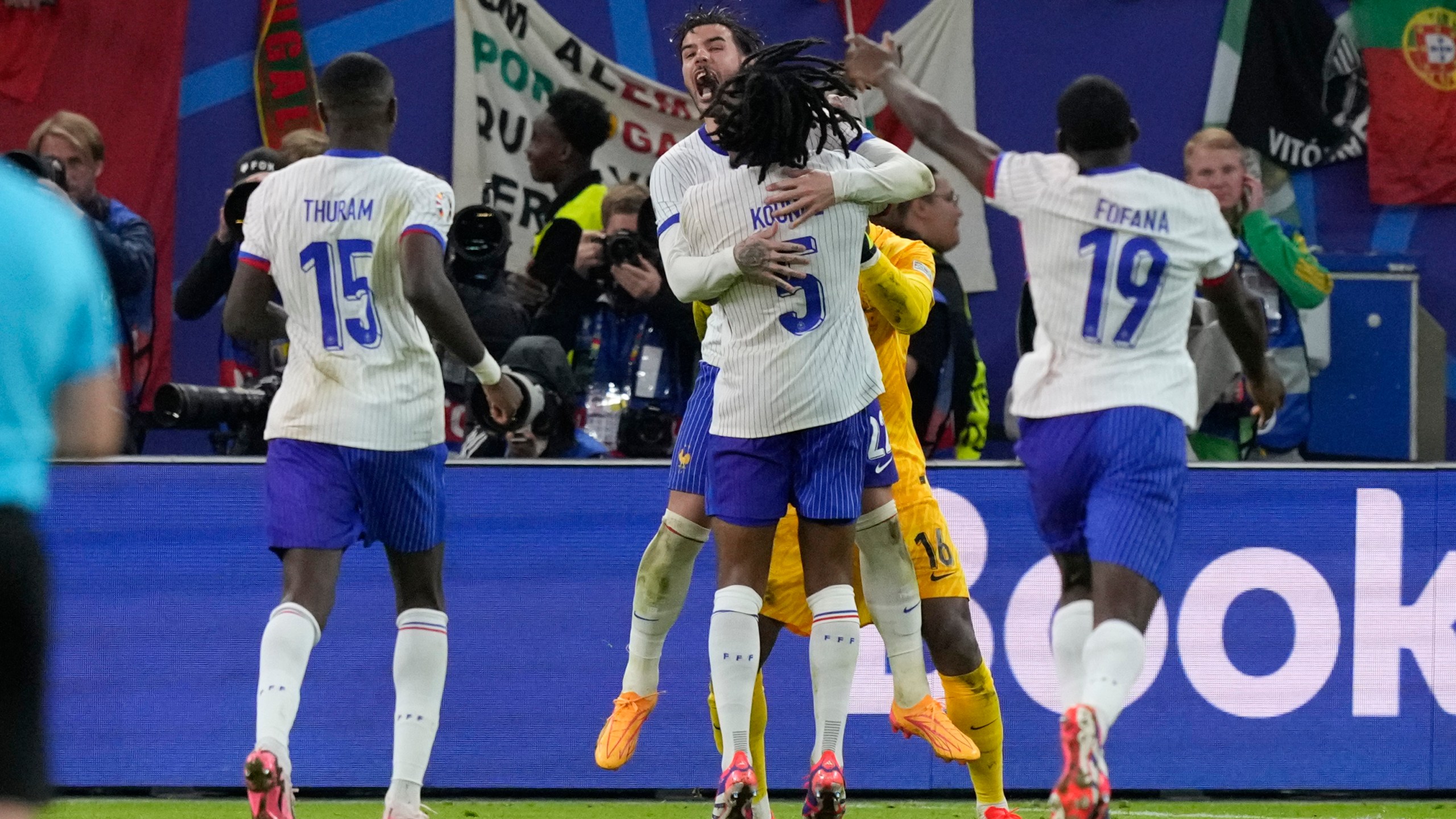 Theo Hernandez of France, top center, and Jules Kounde celebrate after Hernandez scored the deciding goal in a shootout to win a quarter final match between Portugal and France at the Euro 2024 soccer tournament in Hamburg, Germany, Friday, July 5, 2024. (AP Photo/Frank Augstein)