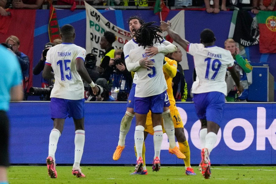 Theo Hernandez of France, top center, and Jules Kounde celebrate after Hernandez scored the deciding goal in a shootout to win a quarter final match between Portugal and France at the Euro 2024 soccer tournament in Hamburg, Germany, Friday, July 5, 2024. (AP Photo/Frank Augstein)