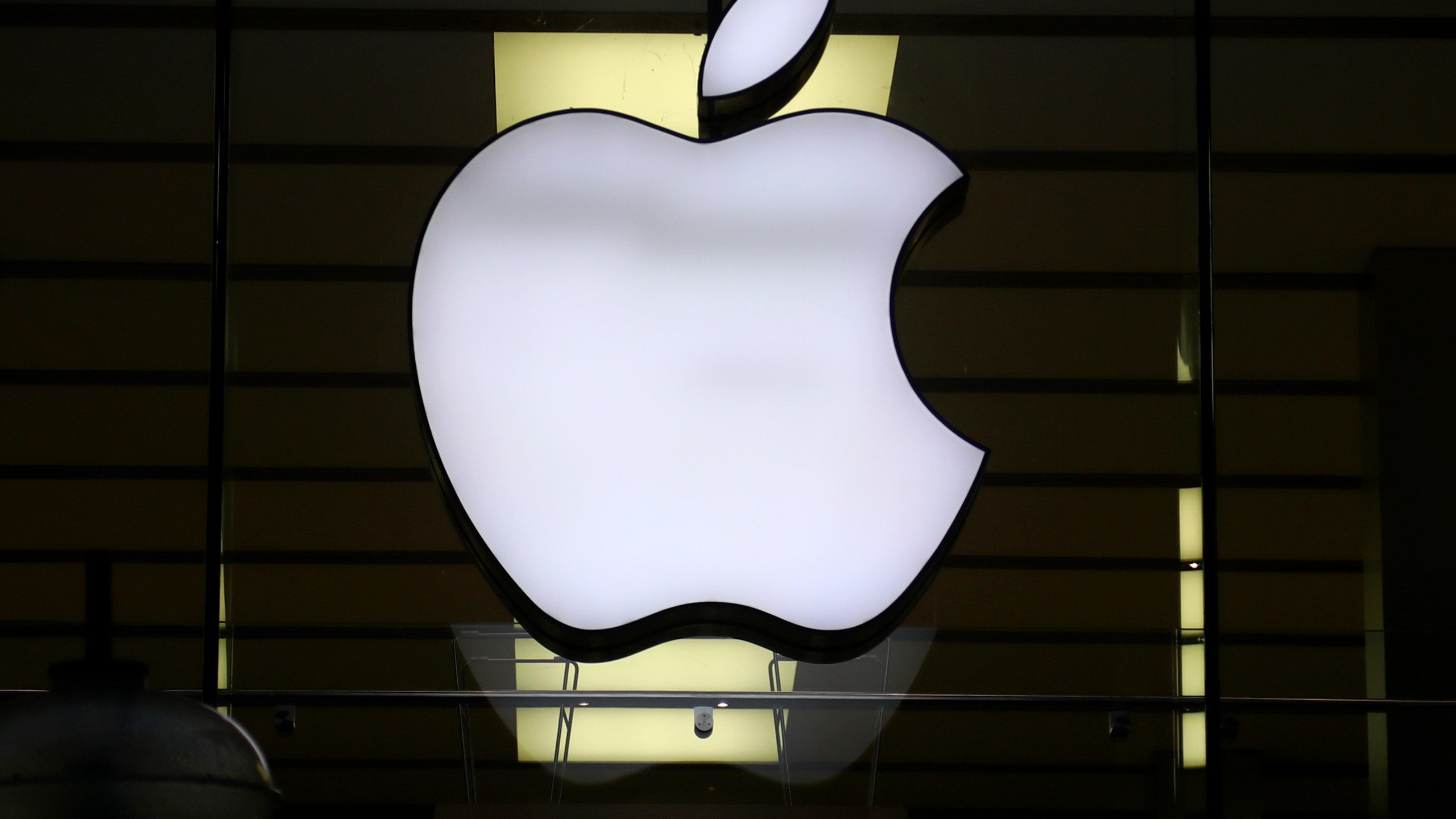 FILE - The logo of Apple is illuminated at a store in the city center in Munich, Germany, on Dec. 16, 2020. The European Union says it's accepting Apple's pledge to open up its tap-and-go mobile payment system to rivals as a way to resolve an antitrust case and head off a hefty fine. (AP Photo/Matthias Schrader, File)